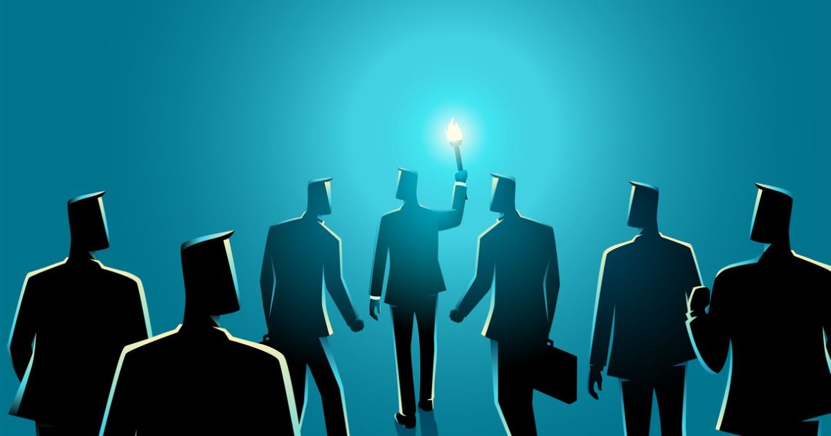 A group of business people are standing around a man holding a light.