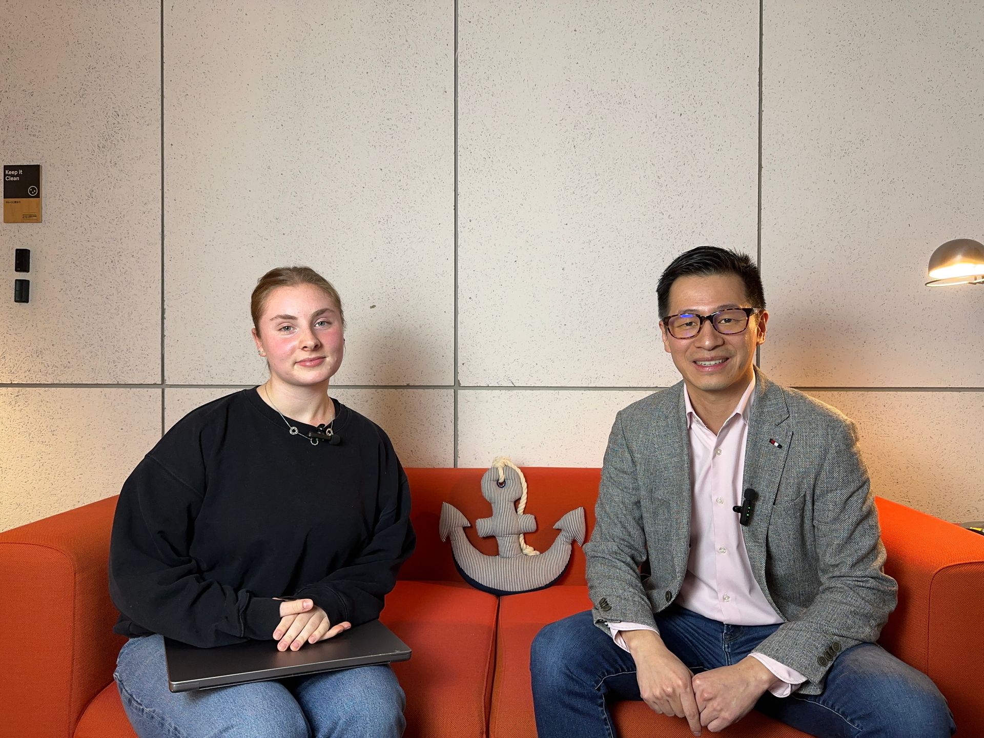 A man and a woman are sitting on an orange couch.