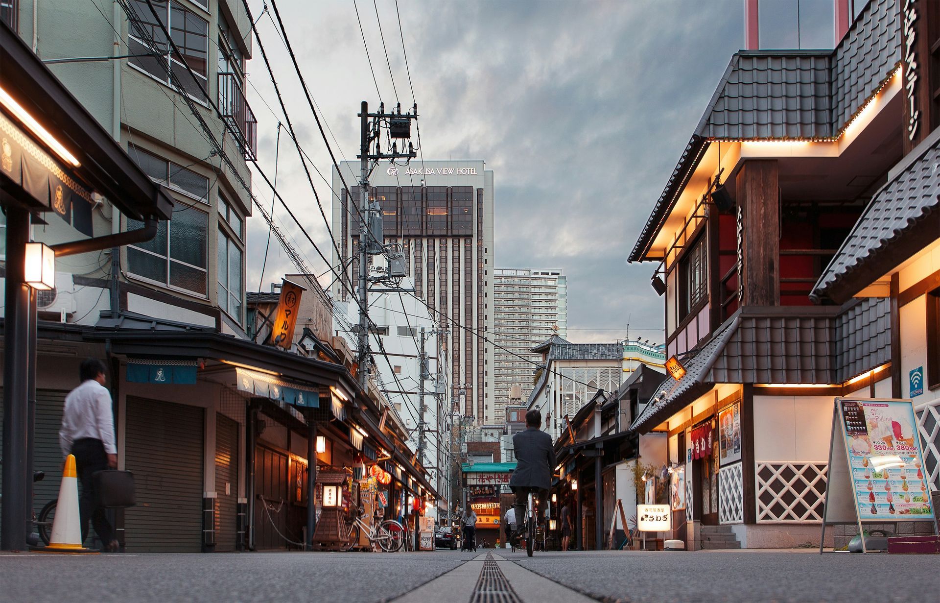A city street with a lot of buildings and people walking down it