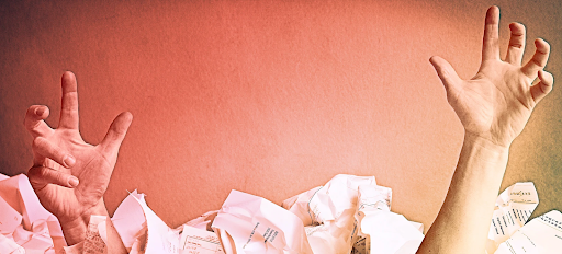 A person 's hands are reaching out from a pile of crumpled paper.