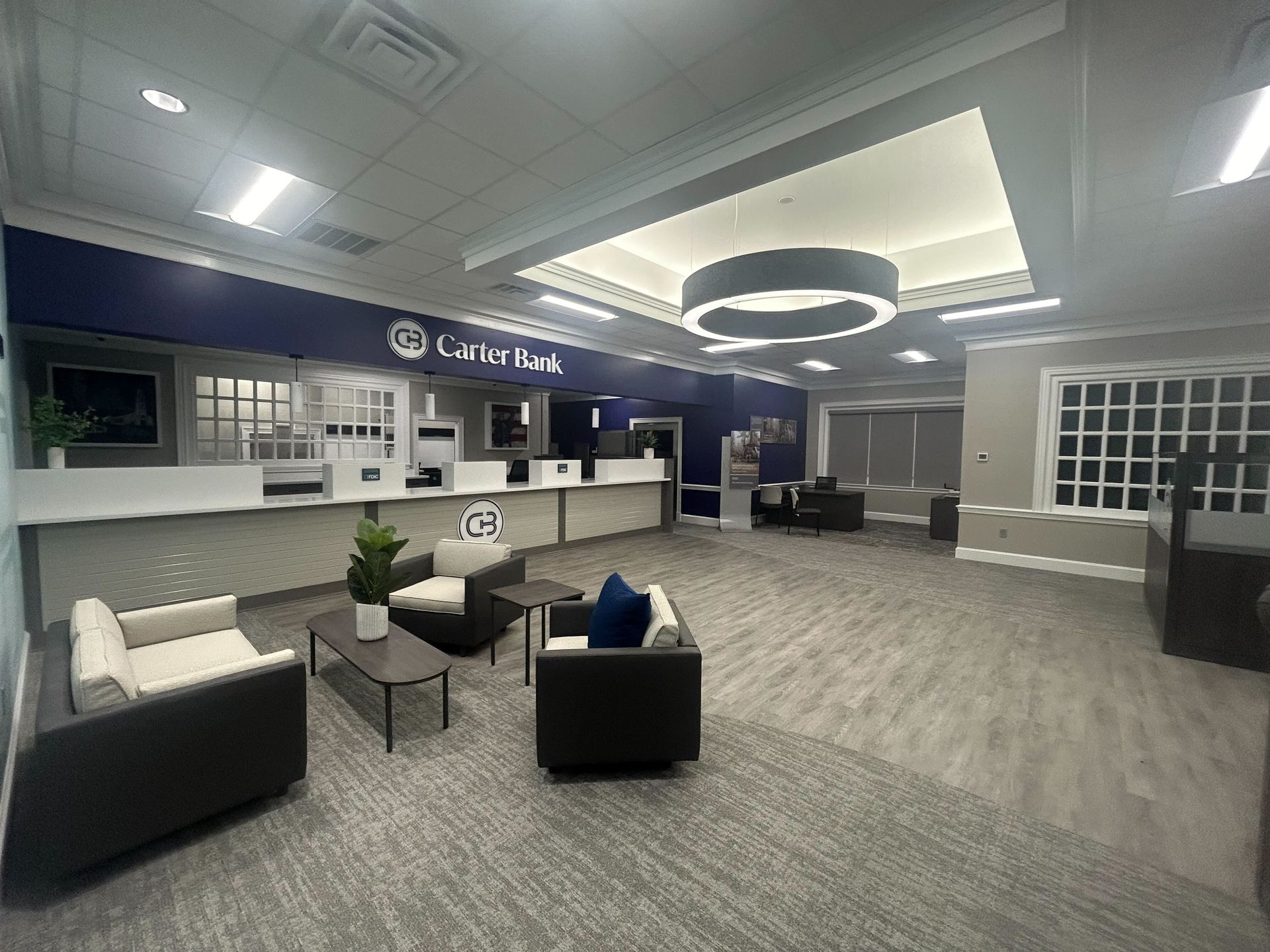 A bank lobby with a couch , chairs , tables and a counter.