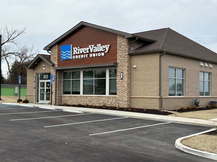 A river valley credit union building with a parking lot in front of it.