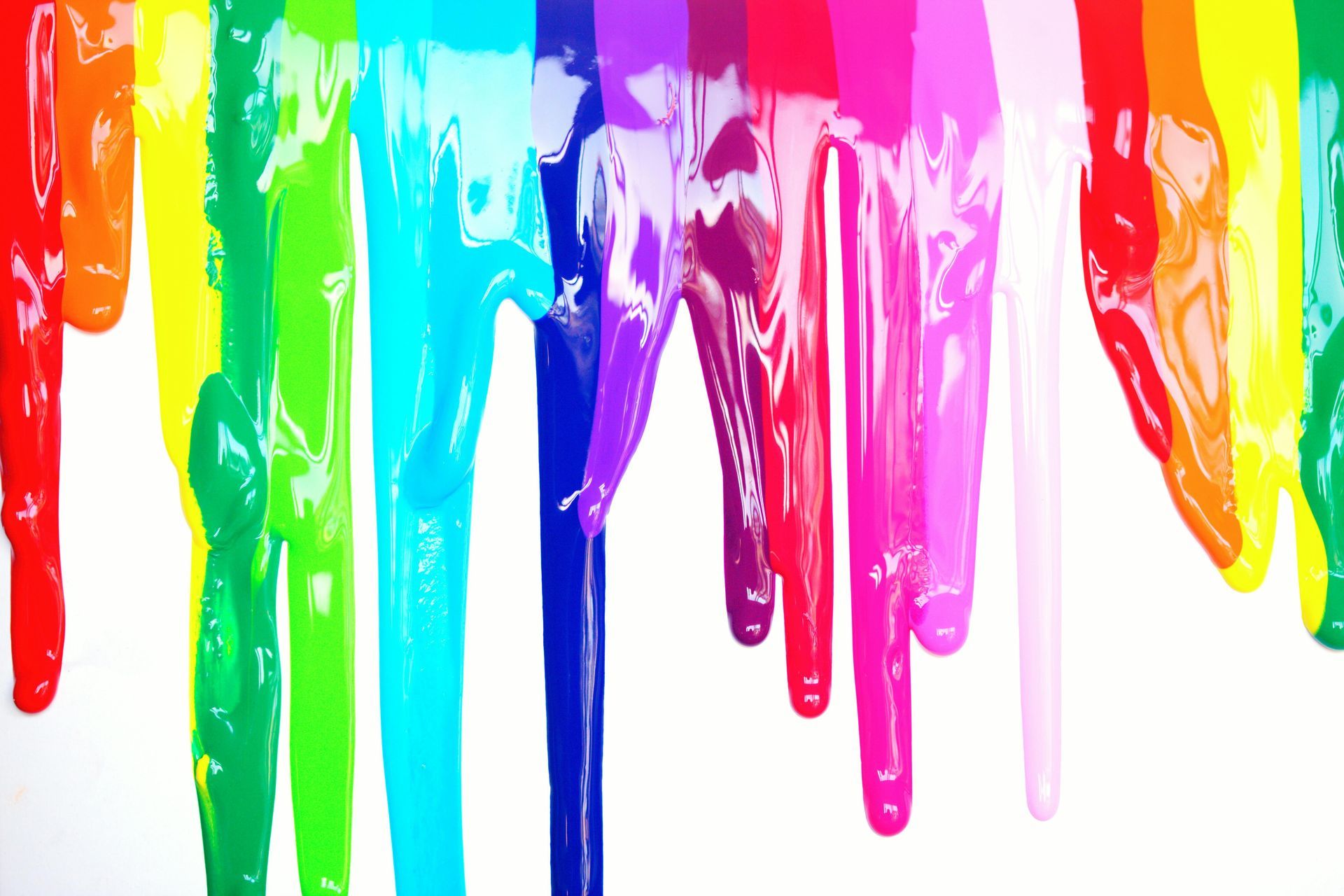 A rainbow of colors is dripping down a white surface.