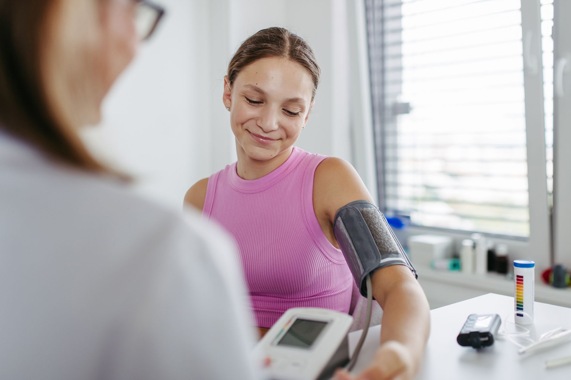 Person getting blood pressure checked by a doctor; woman smiles.