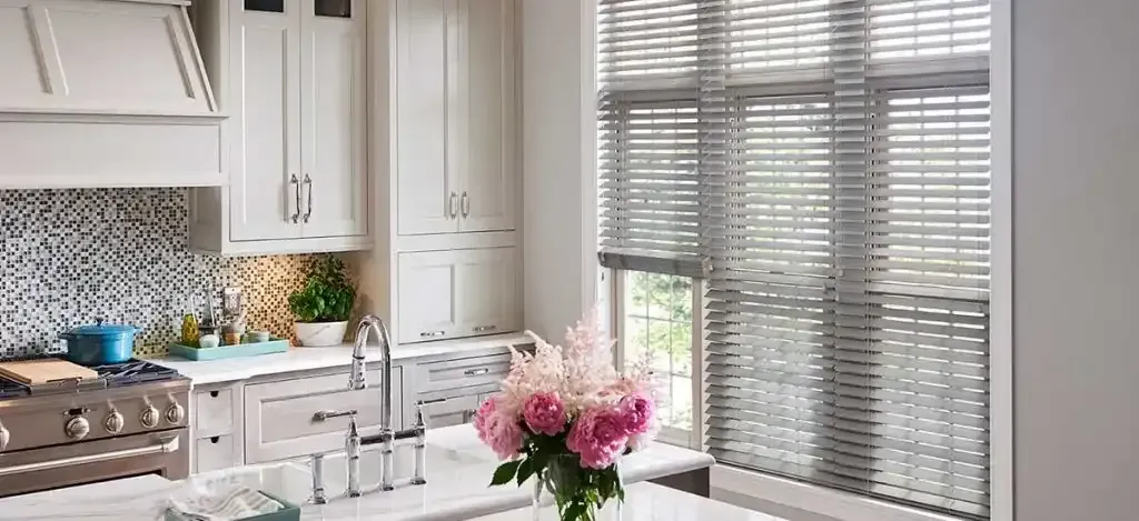 Bright kitchen with white cabinets, stainless steel appliances, and a bouquet of pink flowers.