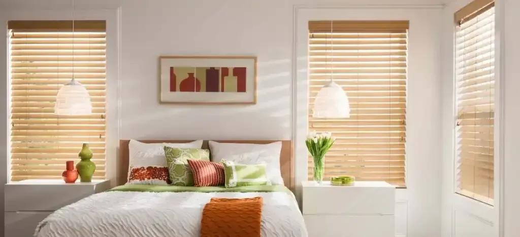 Bedroom with a bed, two windows with blinds, two pendant lights, and decorative objects.