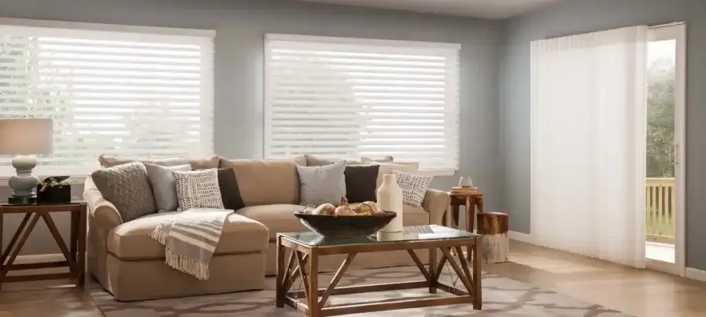 Living room with beige couch, coffee table, and large windows with blinds.