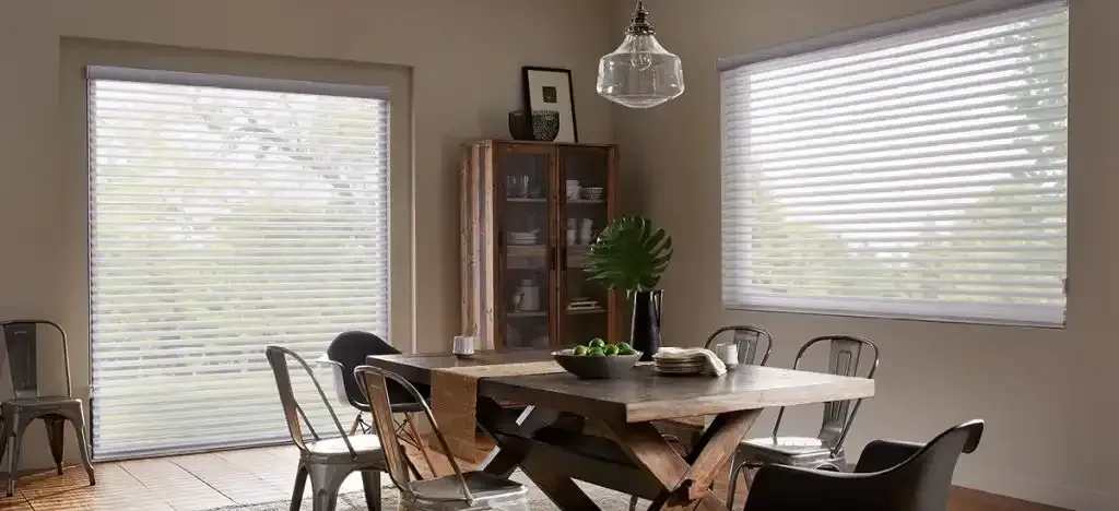 Dining room with wooden table, chairs, glass cabinet, pendant light, and window blinds.