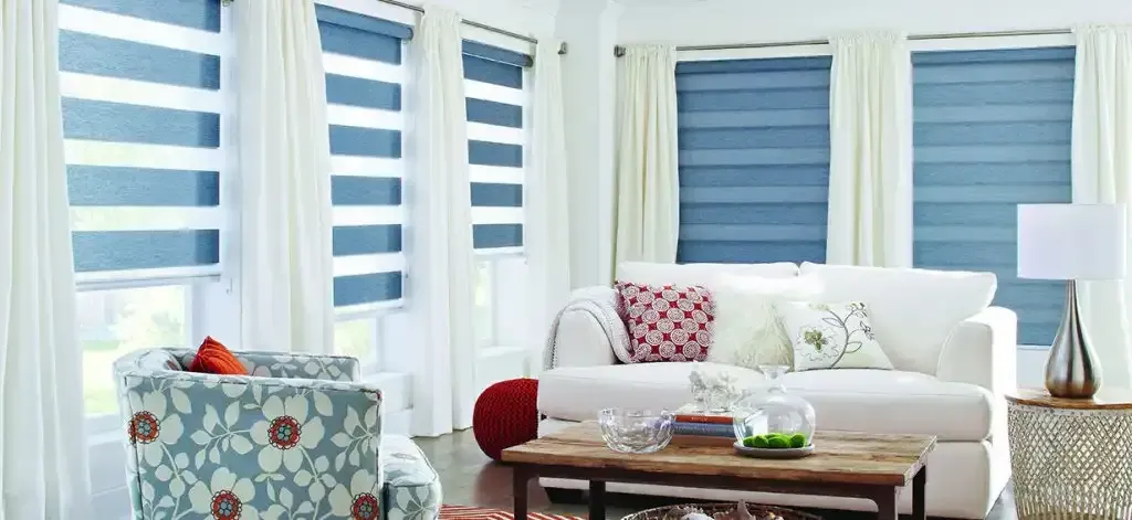 Living room with blue striped blinds, white curtains, and a white sofa with pillows.