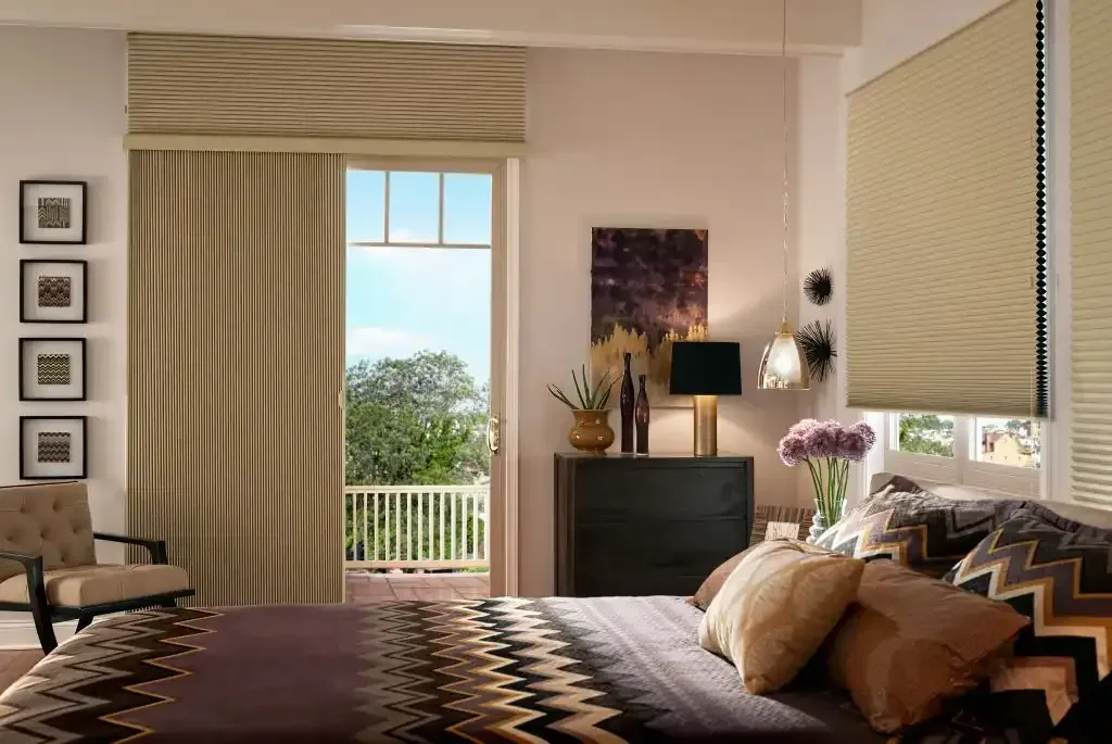 Bedroom interior with a bed, dresser, door to a balcony, and window with blinds.