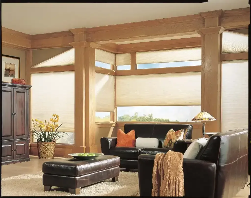 Living room with brown leather furniture, beige window shades, and wooden beams.