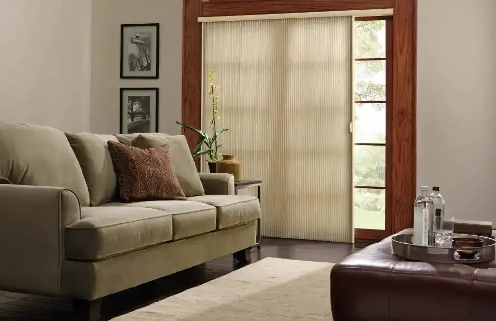 Living room with beige couch, window shades, and a wooden framed door.