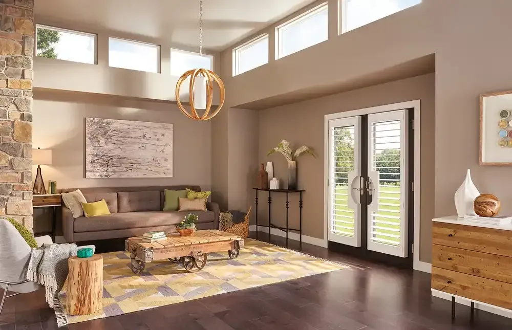 Living room with brown walls, dark wood floor, stone accent wall, and large windows.