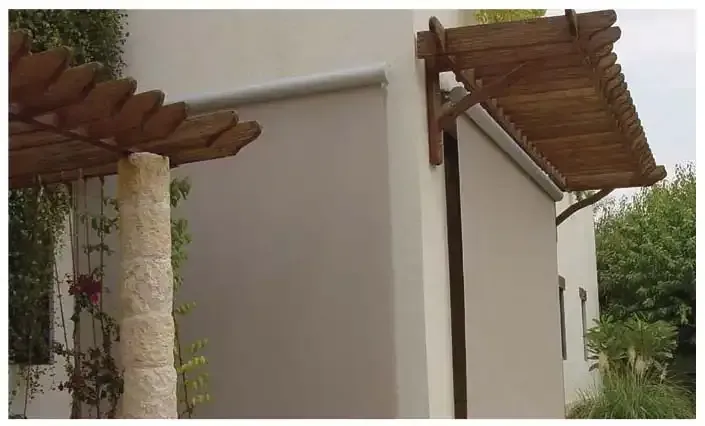 Wooden pergola and beige awning on a white building exterior.