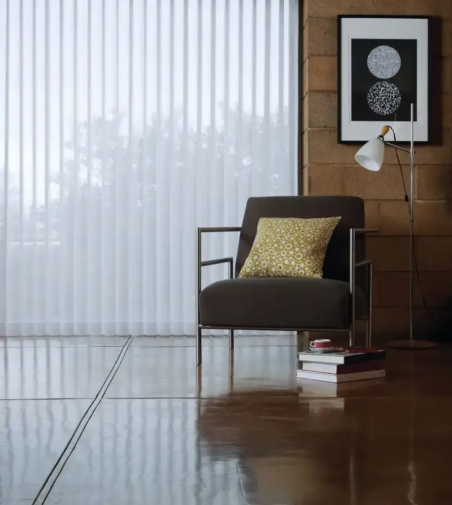 Living room with chair, pillow, floor lamp, art, and vertical blinds.