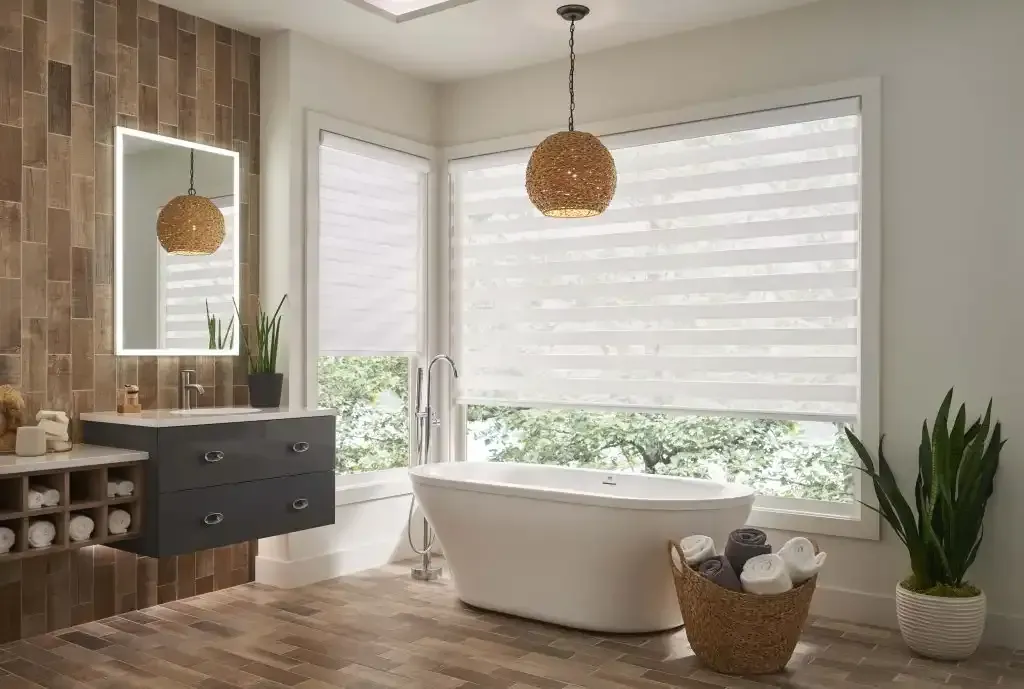 Bathroom with a white bathtub, sheer window shades, wooden flooring, and a decorative light fixture.