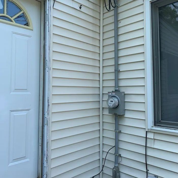 White house exterior with a gray electric meter and conduit.