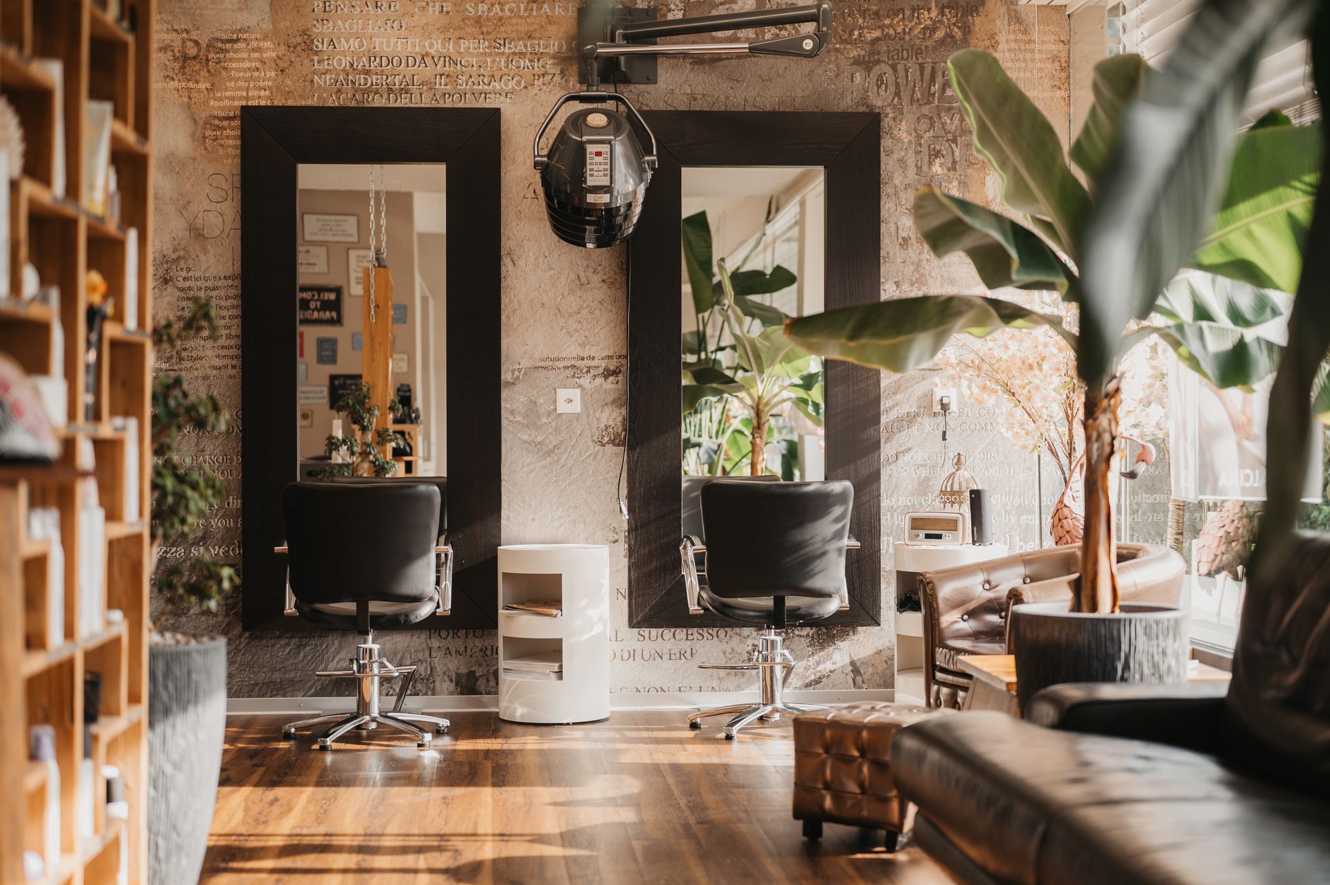 Saloninterieur mit Spiegeln, Stühlen, Pflanzen und freigelegter Ziegelwand.