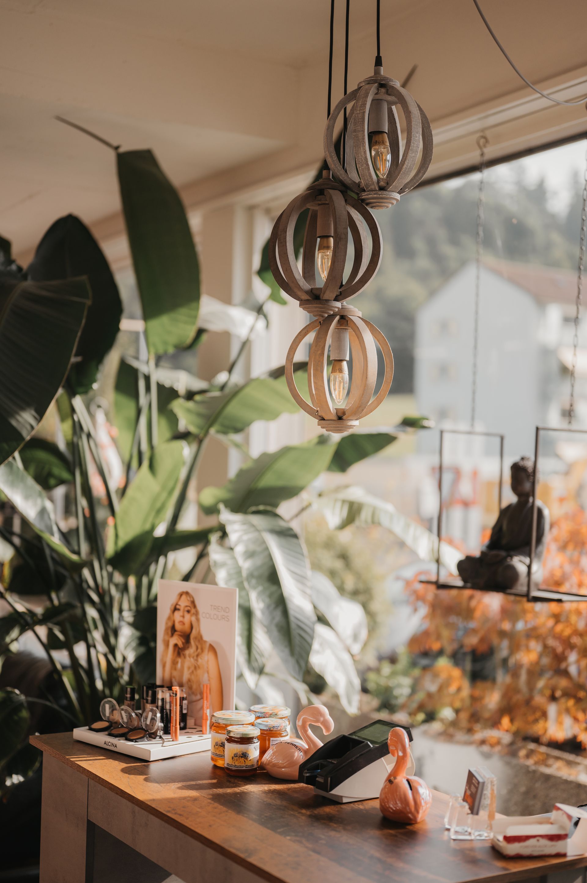 Küchentheke mit Pflanzen, Holzleuchten und Buddha-Statue. Sonnenlicht strömt durch ein großes Fenster herein.