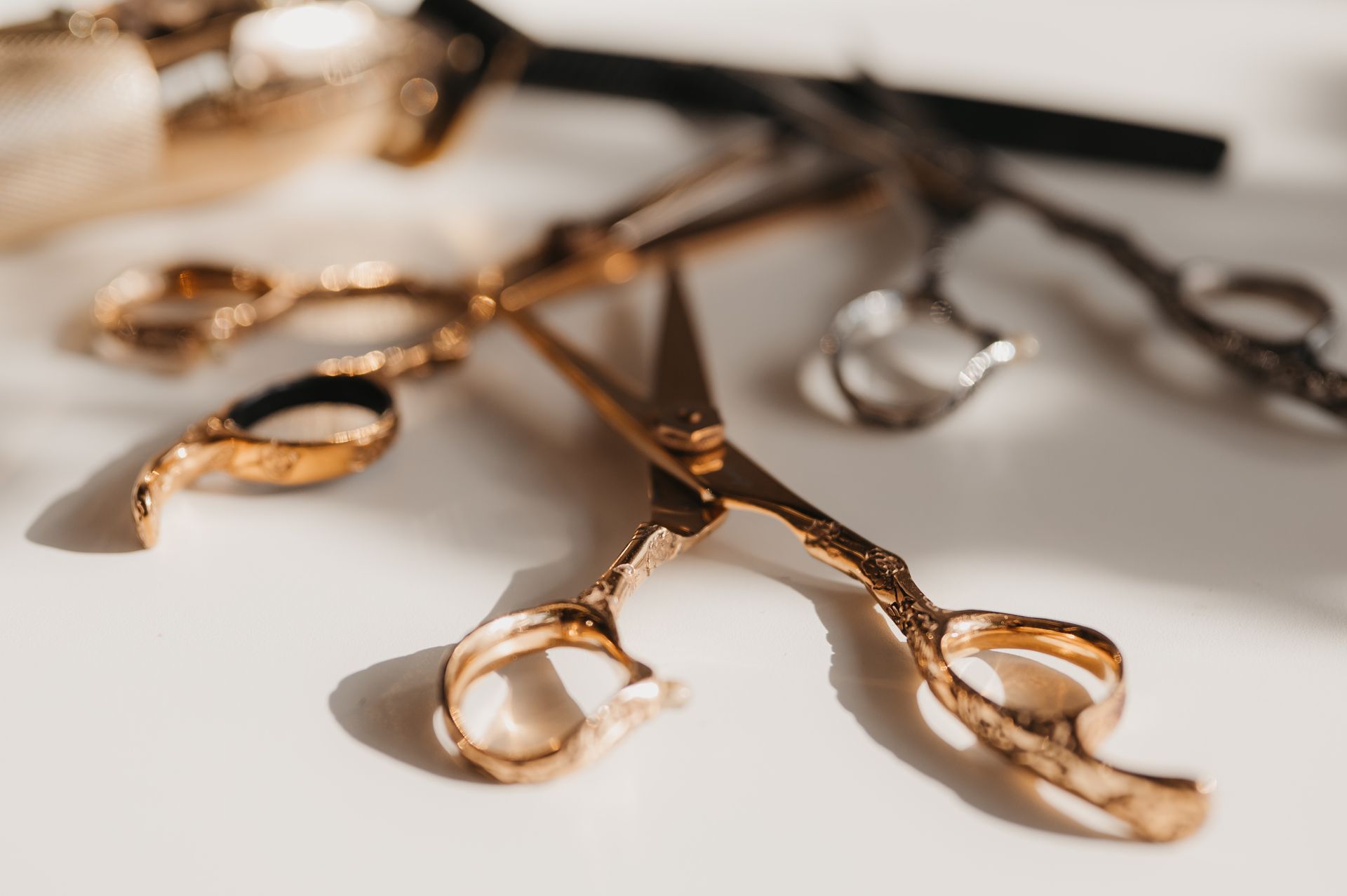 Goldene und silberne Friseurschere auf weißem Untergrund, Nahaufnahme.