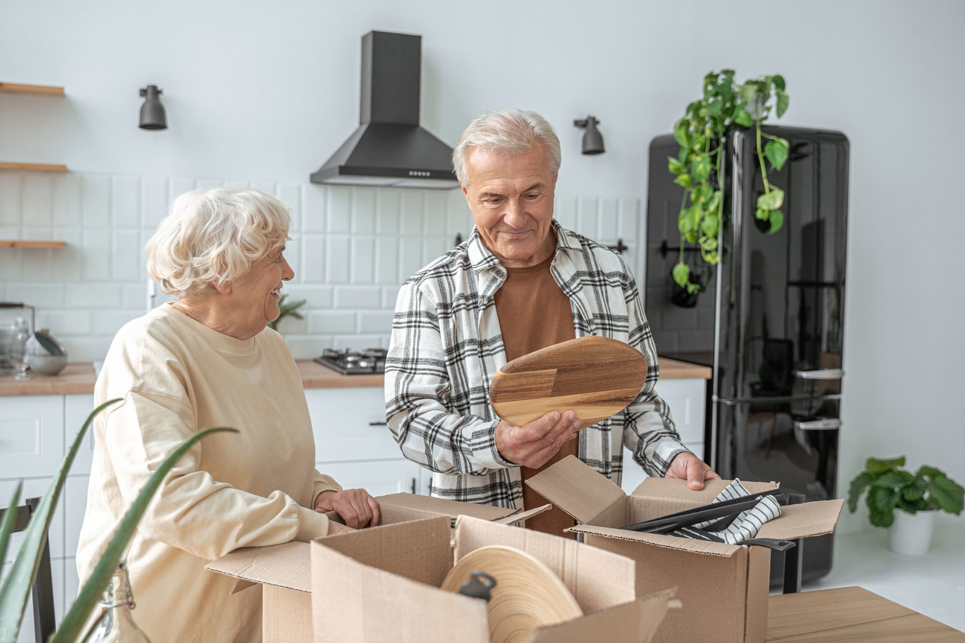 Mature couple standing in the kitchen with moving boxes at their new home.