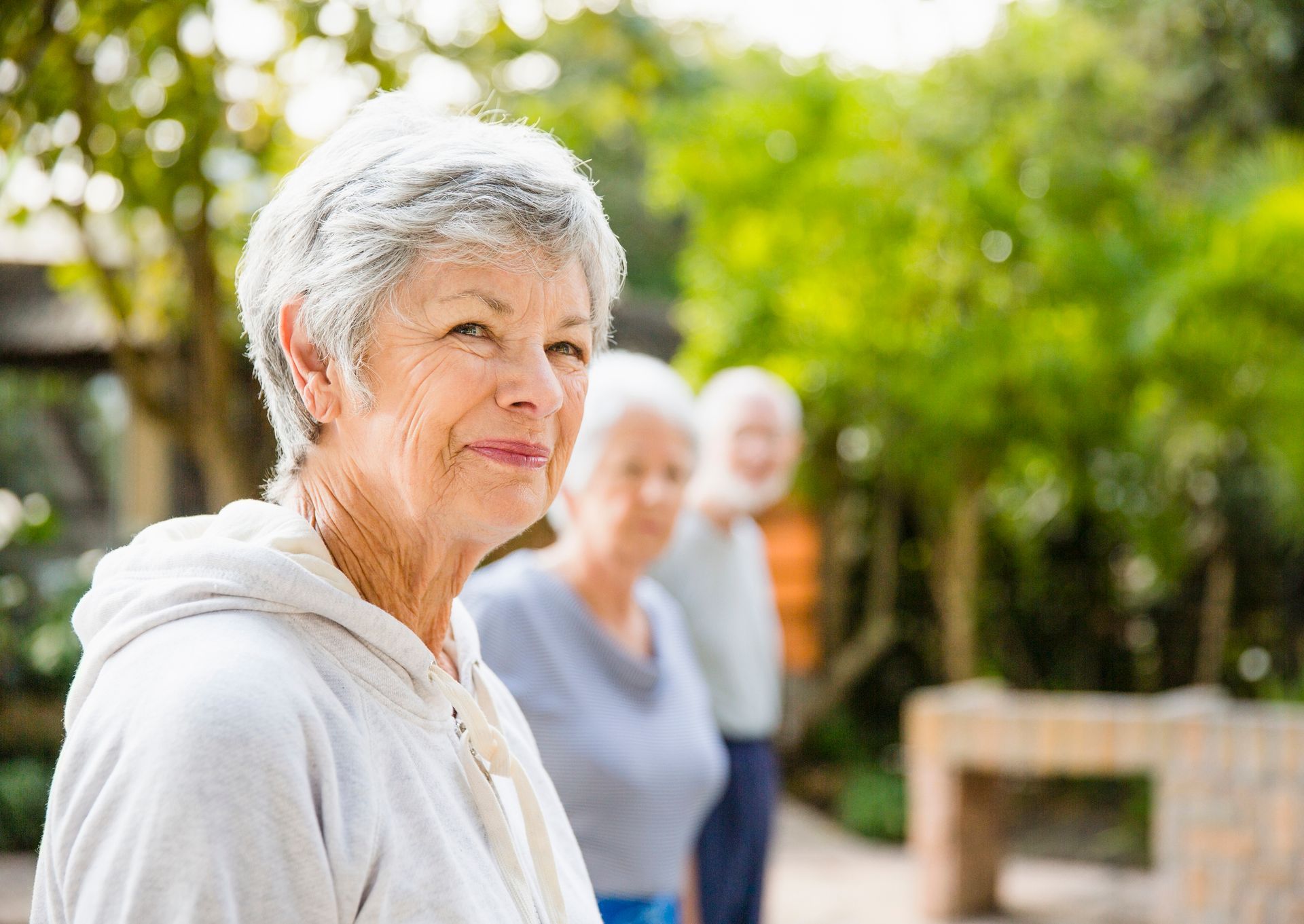 Senior woman looking away with friends in background at yard.