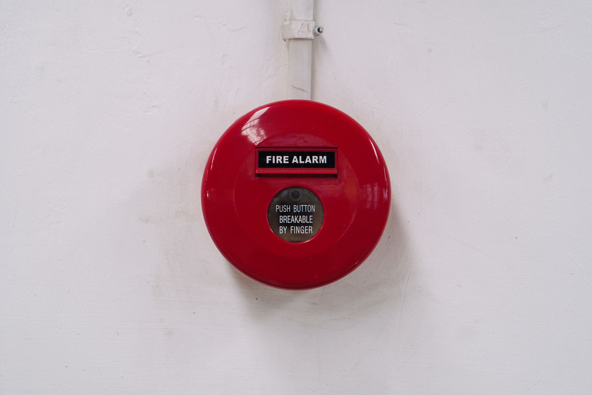 A red fire alarm mounted on a white wall.
