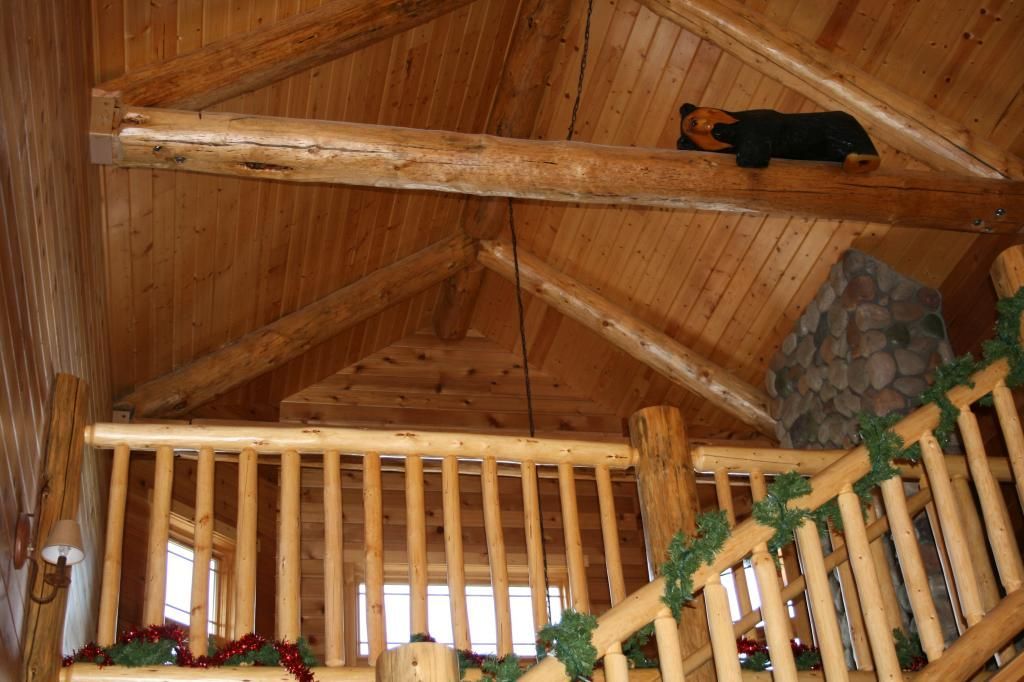 A wooden staircase in a cabin with a bear on the ceiling