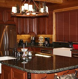 A kitchen with stainless steel appliances, granite counter top , wooden cabinets and a chandelier.