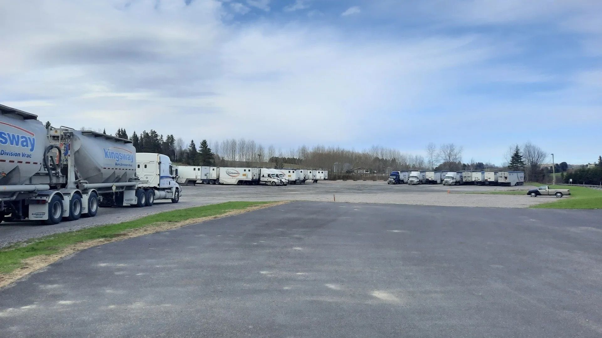 Camions stationnés sur un parking goudronné, ciel couvert.