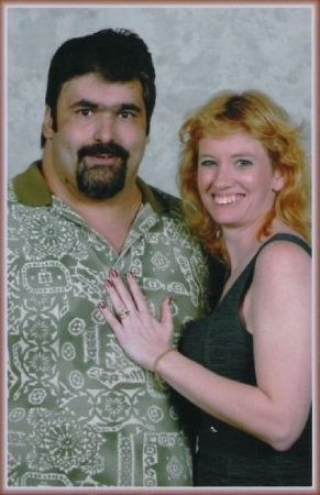 A man with a beard and a woman with red hair are posing for a picture