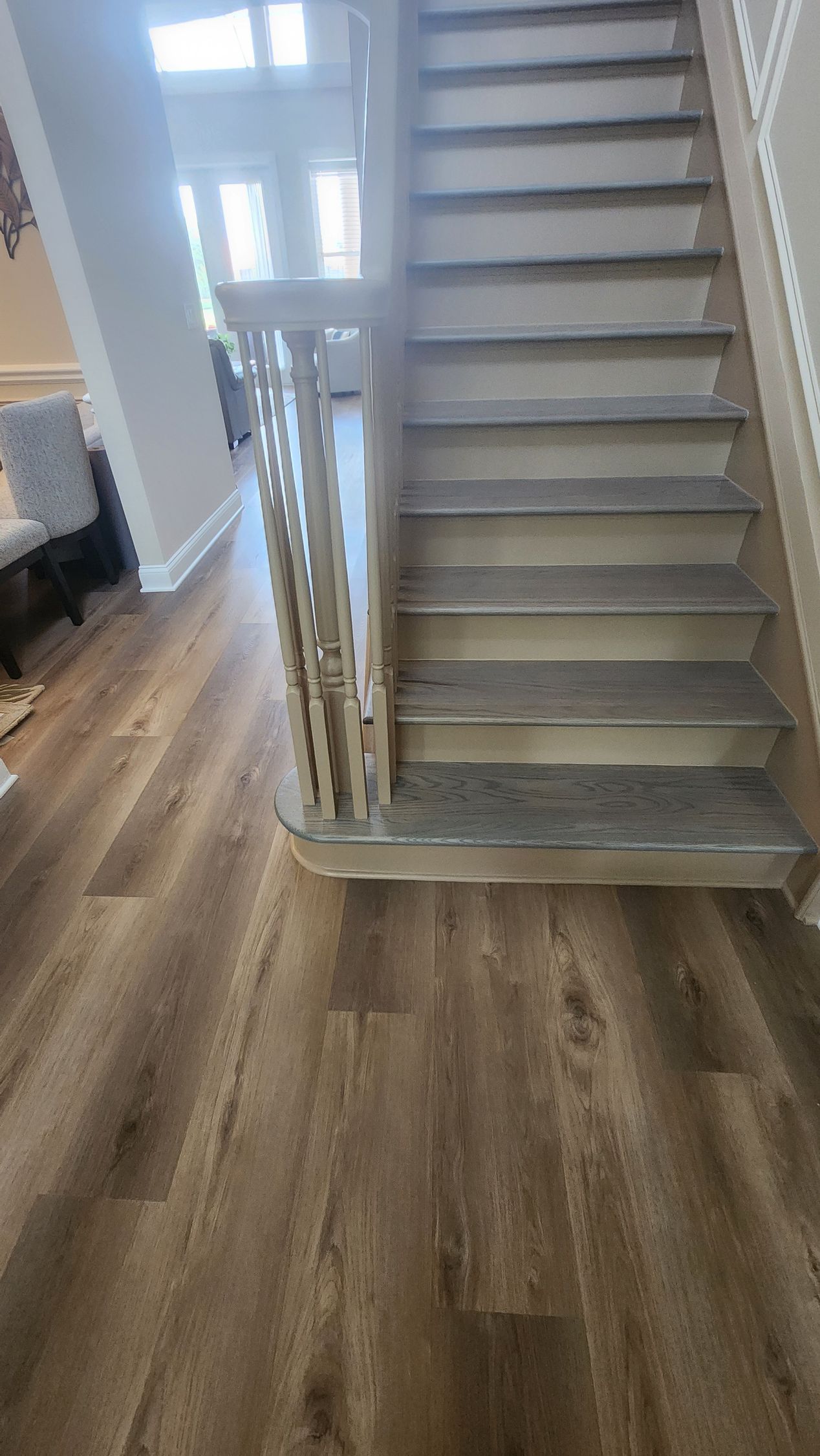 A wooden staircase with grey carpeted treads and a decorative white spindle railing in a home interior.