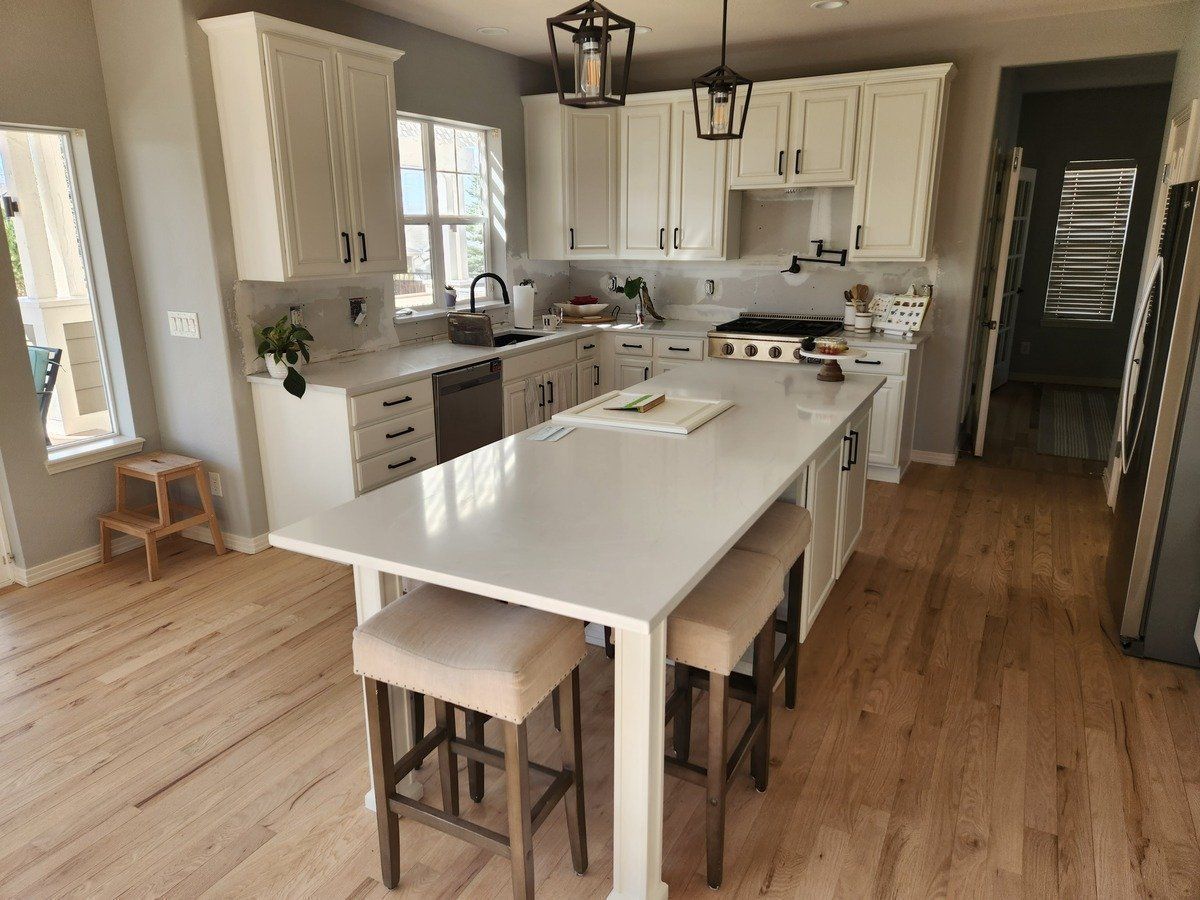 A kitchen with white cabinets and a large island in the middle.