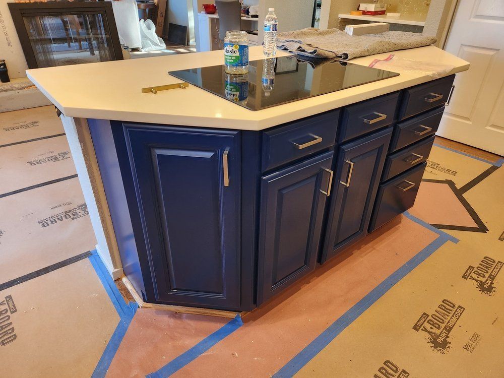 A kitchen island with blue cabinets and a stove top oven.
