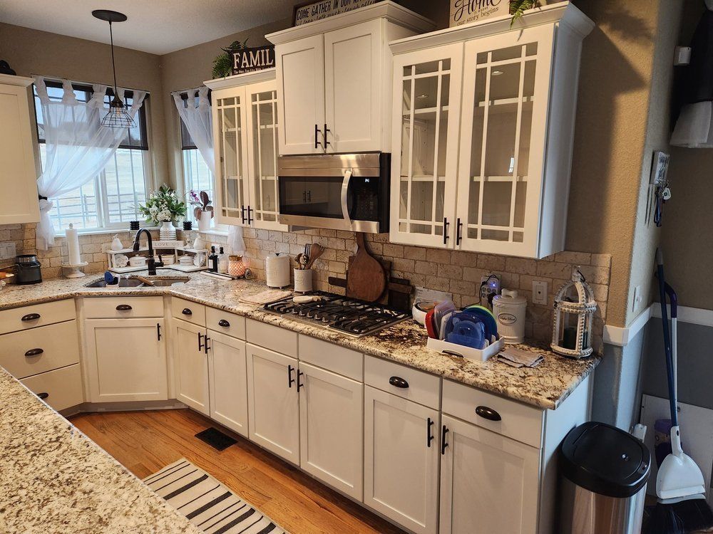 A kitchen with white cabinets and granite counter tops.