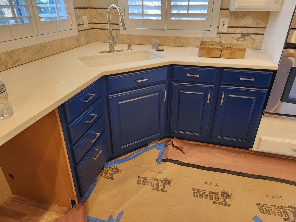 A kitchen with blue cabinets and white counter tops