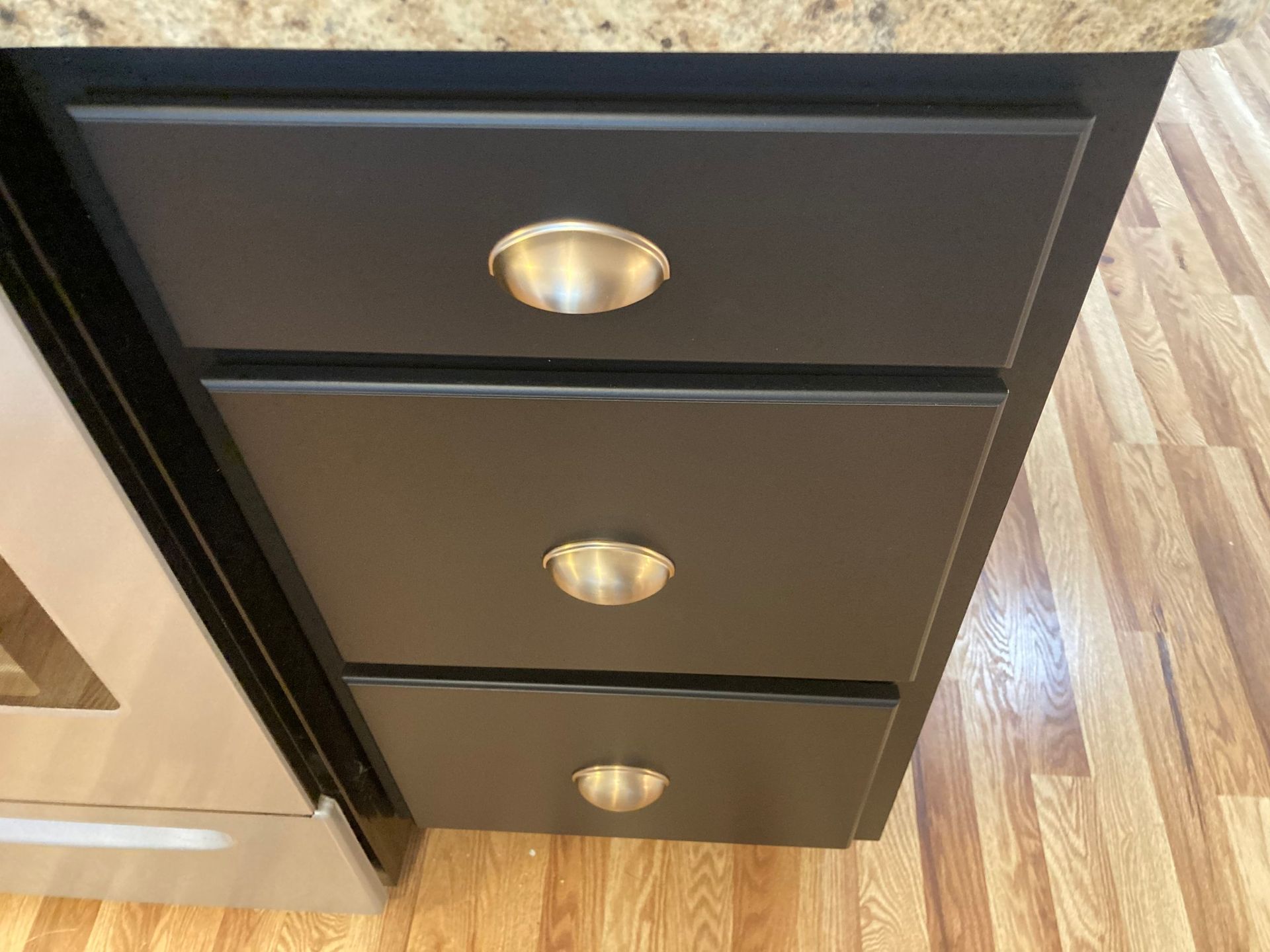 A kitchen with black cabinets and gold handles