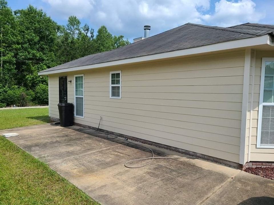 Beige house exterior with a concrete patio, a trash can, and a window.