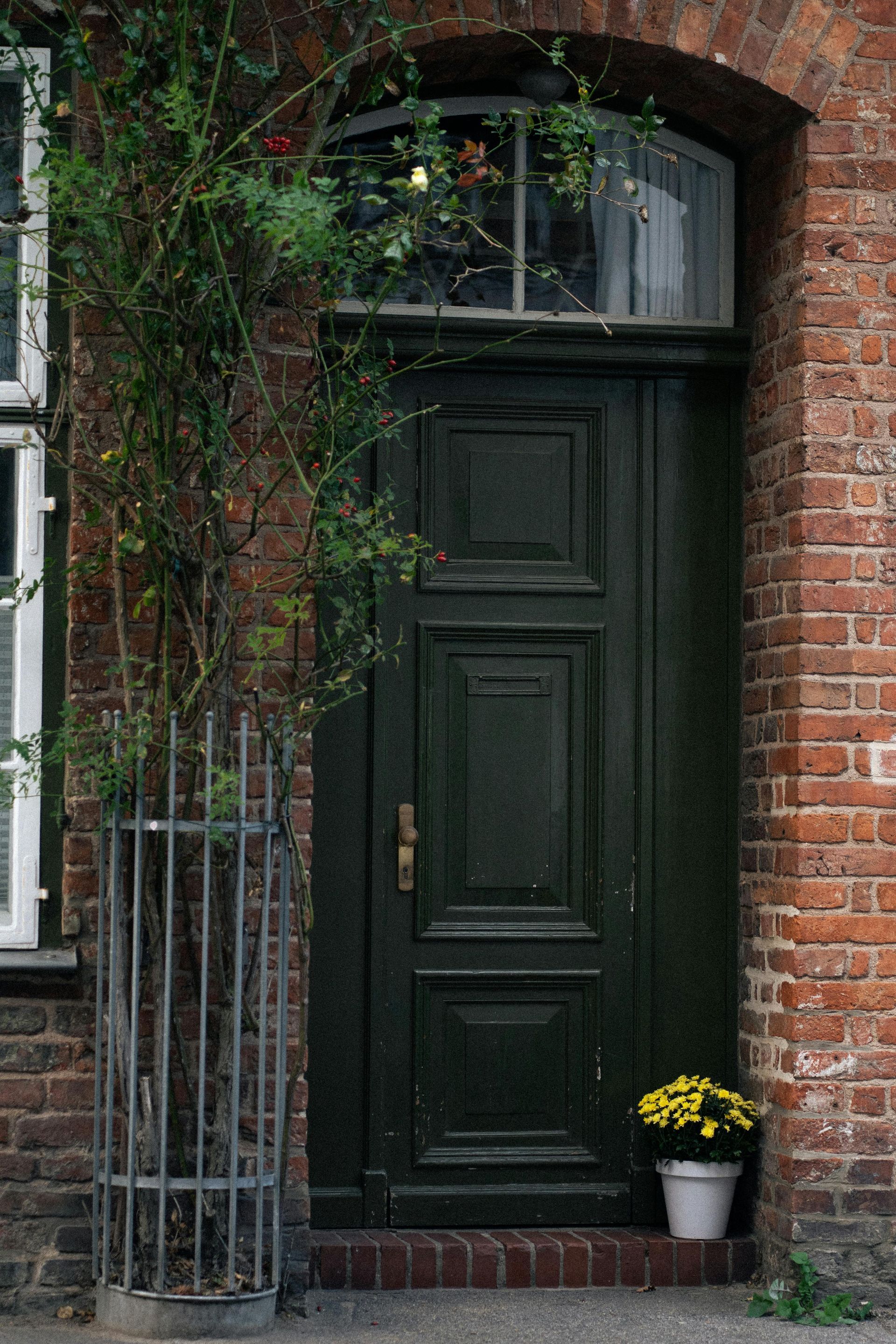 Living room with couch, TV, and stairs. Large window with curtains and a rug.