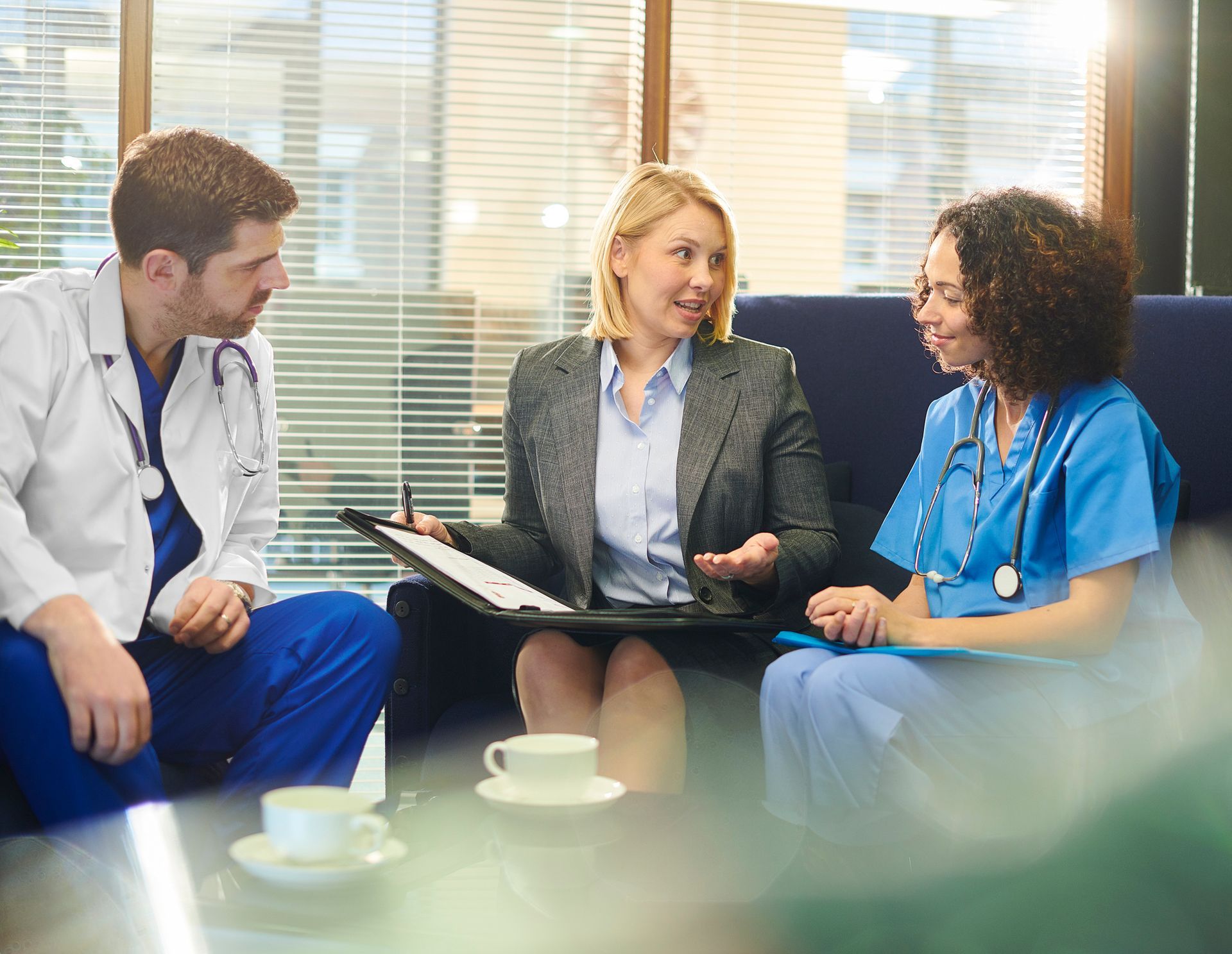 A group of doctors and nurses are sitting on a couch having a meeting.