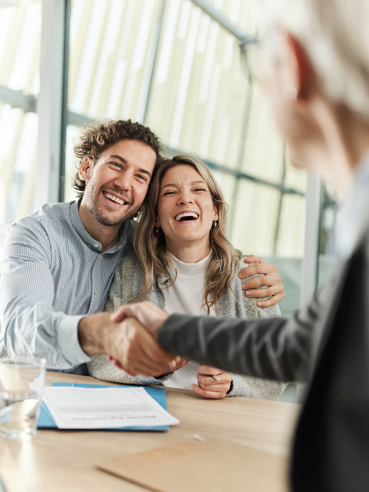 A man and woman are shaking hands with a woman while sitting at a table.