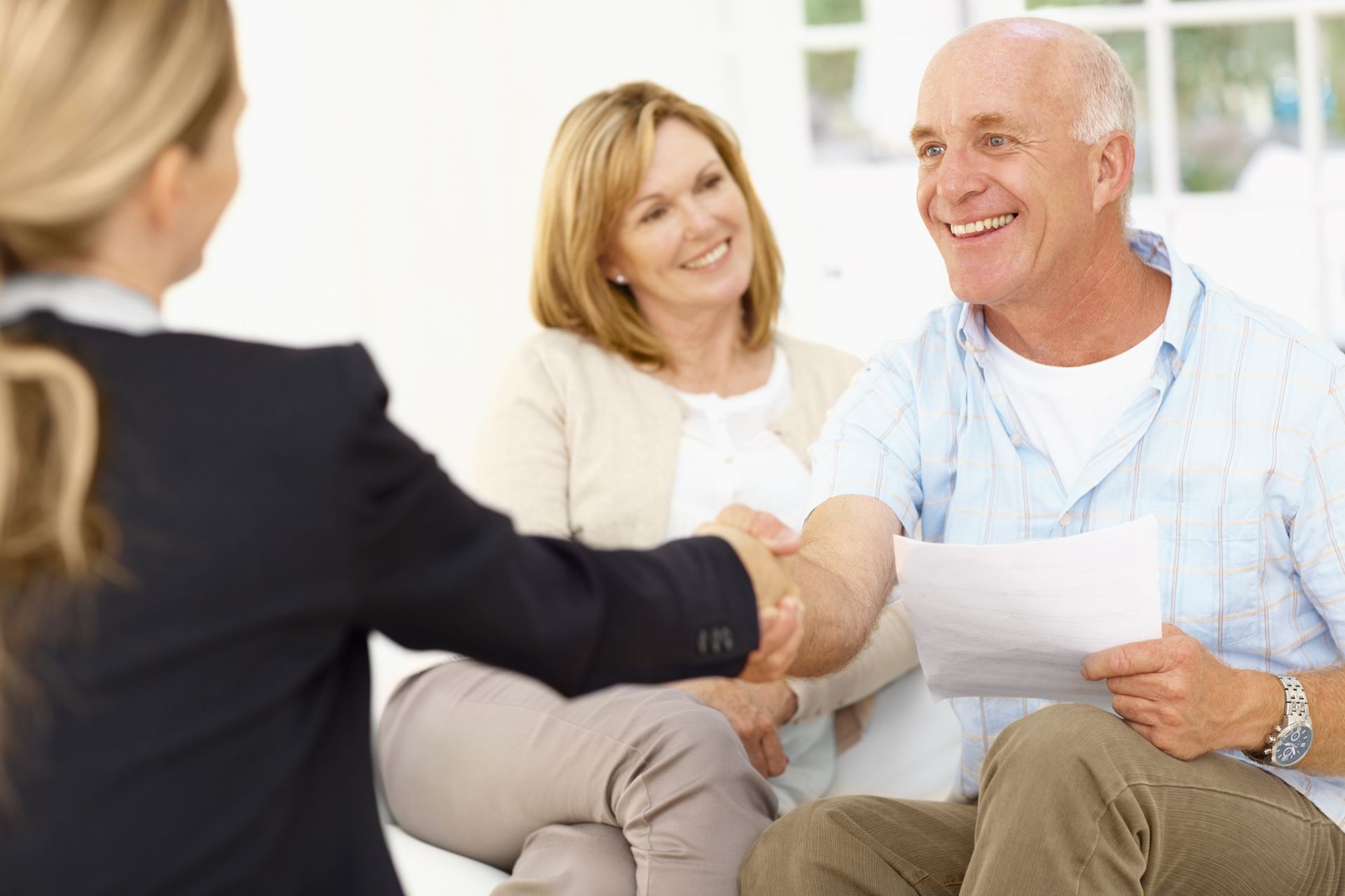 A man and woman are shaking hands with a woman while sitting on a couch.