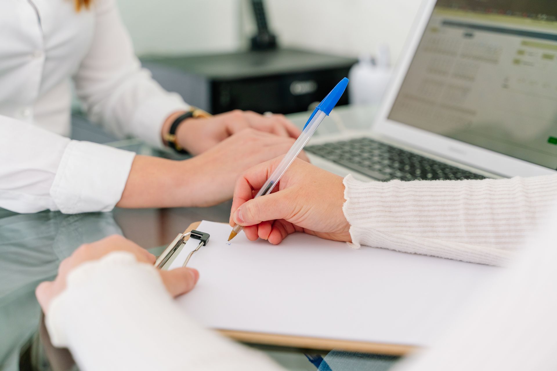 A woman is holding another woman 's hand while writing on a clipboard.