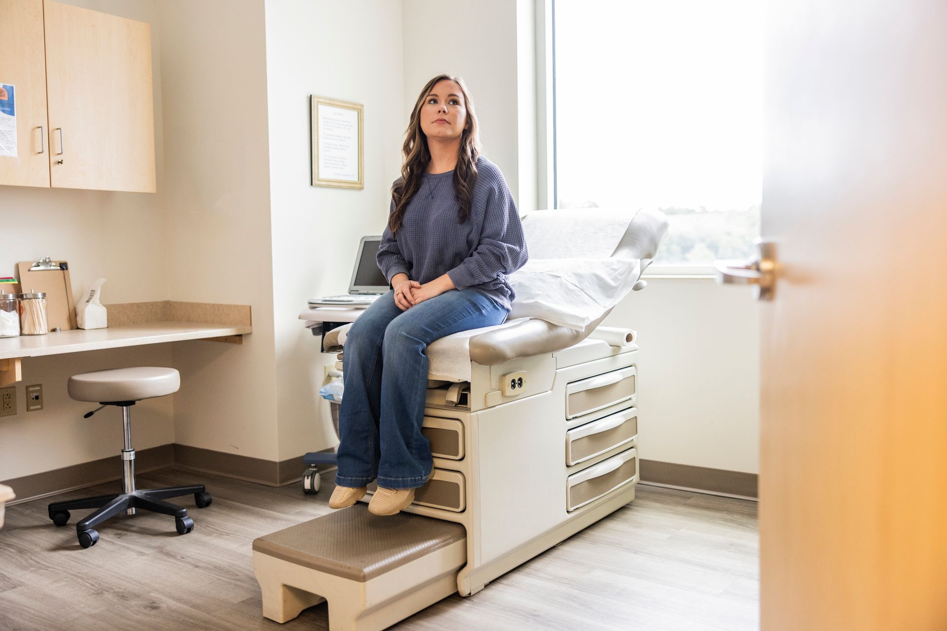 A woman is sitting on an exam table in a doctor 's office.