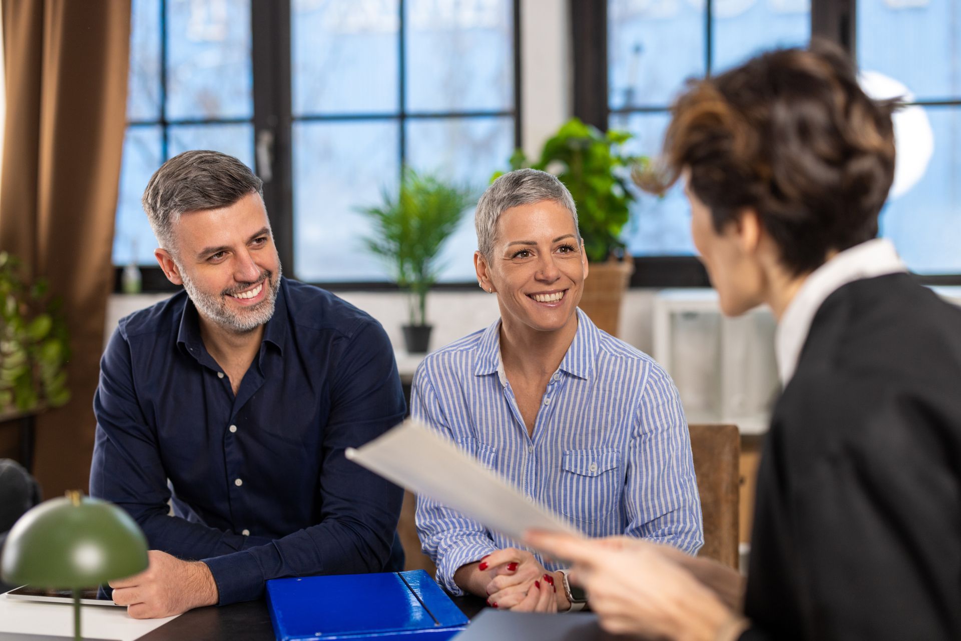 A man and a woman are sitting at a table talking to a woman.