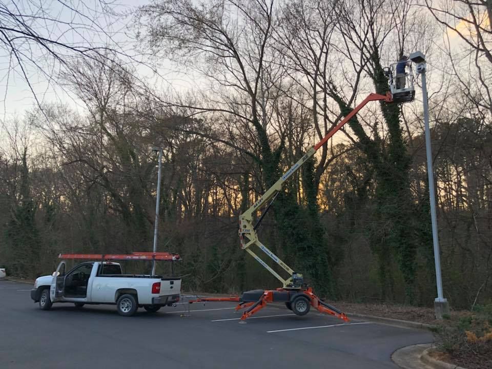 A white truck is parked on the side of the road next to a crane.