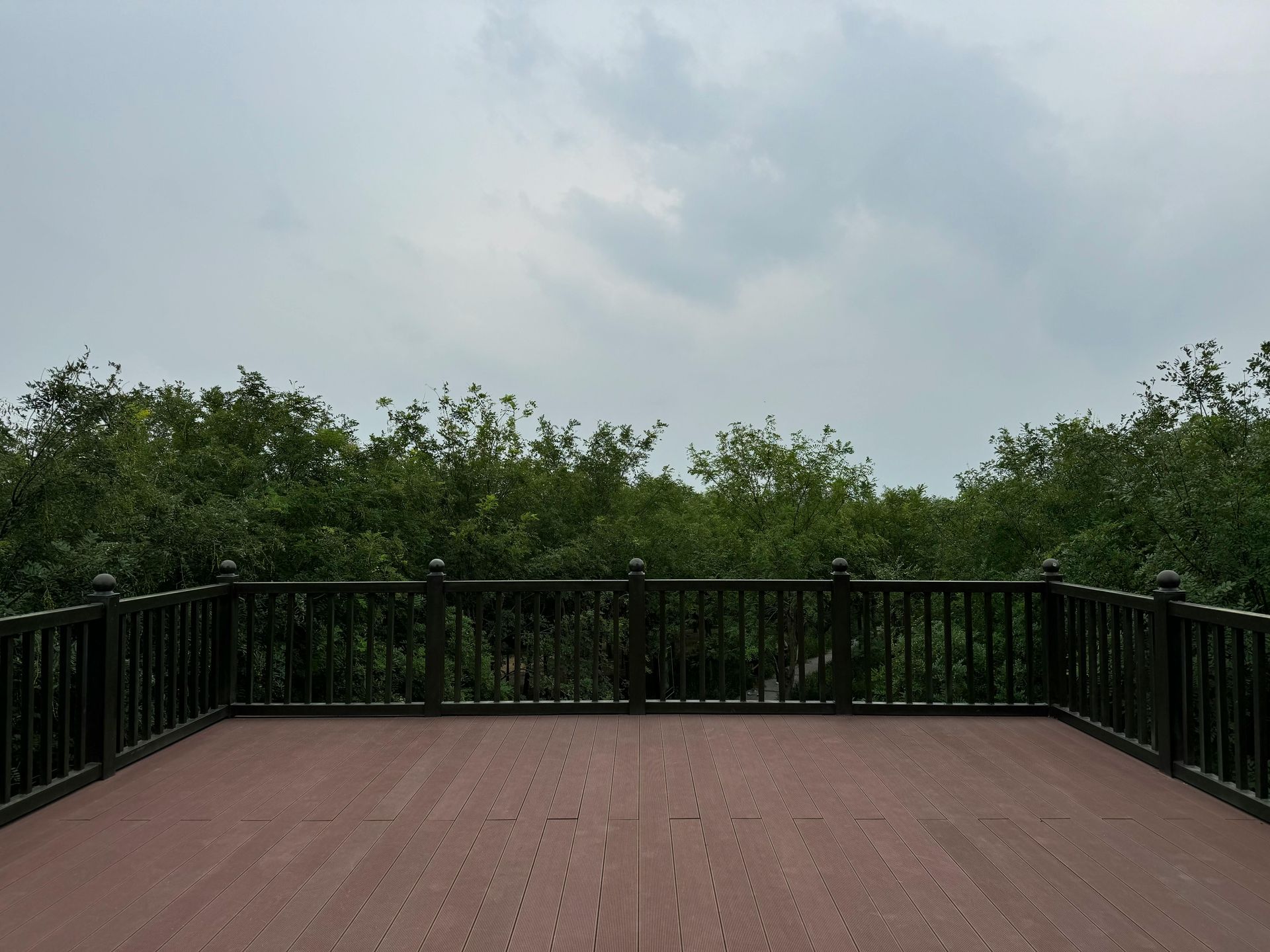 An empty deck with trees in the background and a cloudy sky