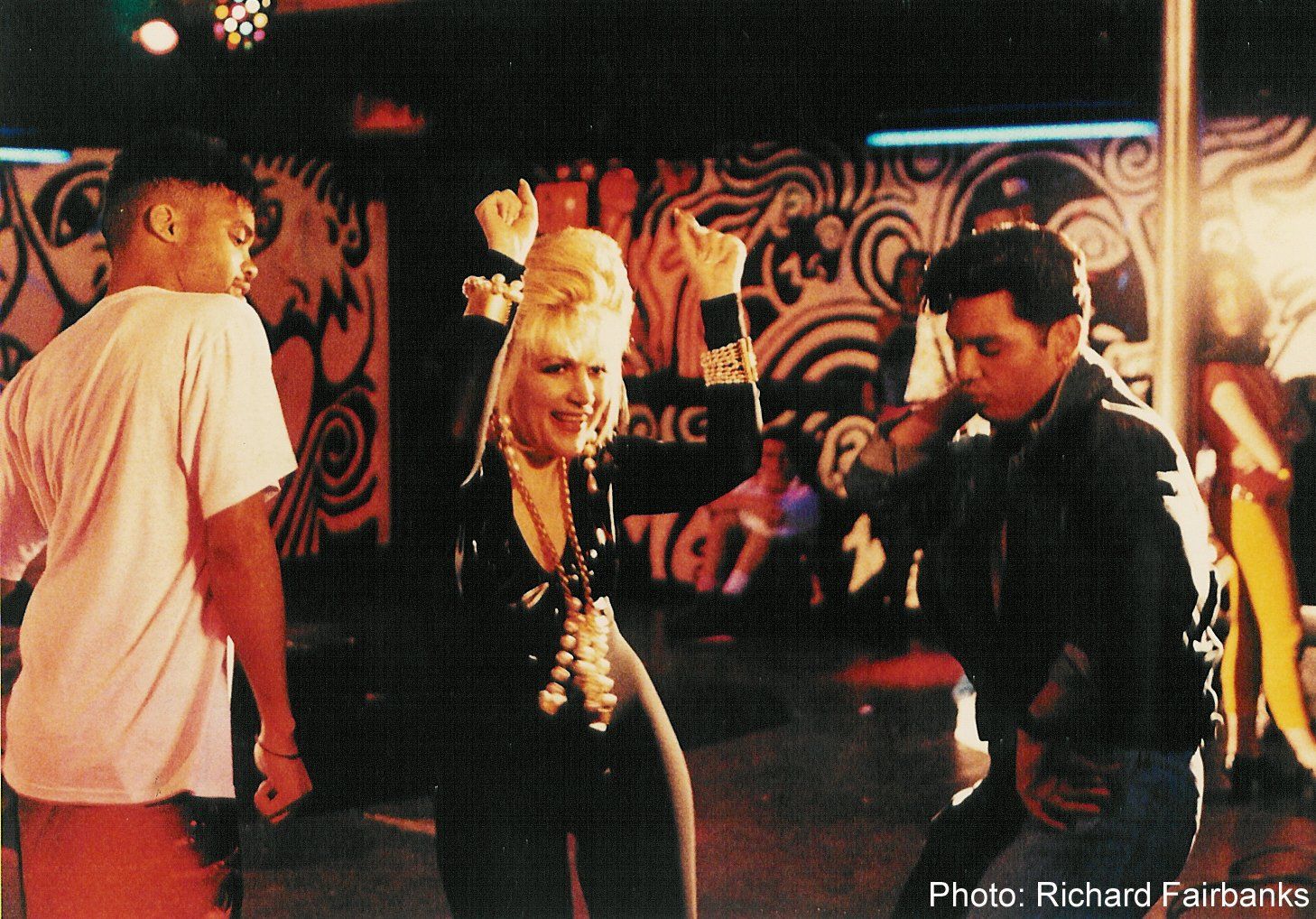 A group of people are dancing in front of a wall that has the number 147 on it