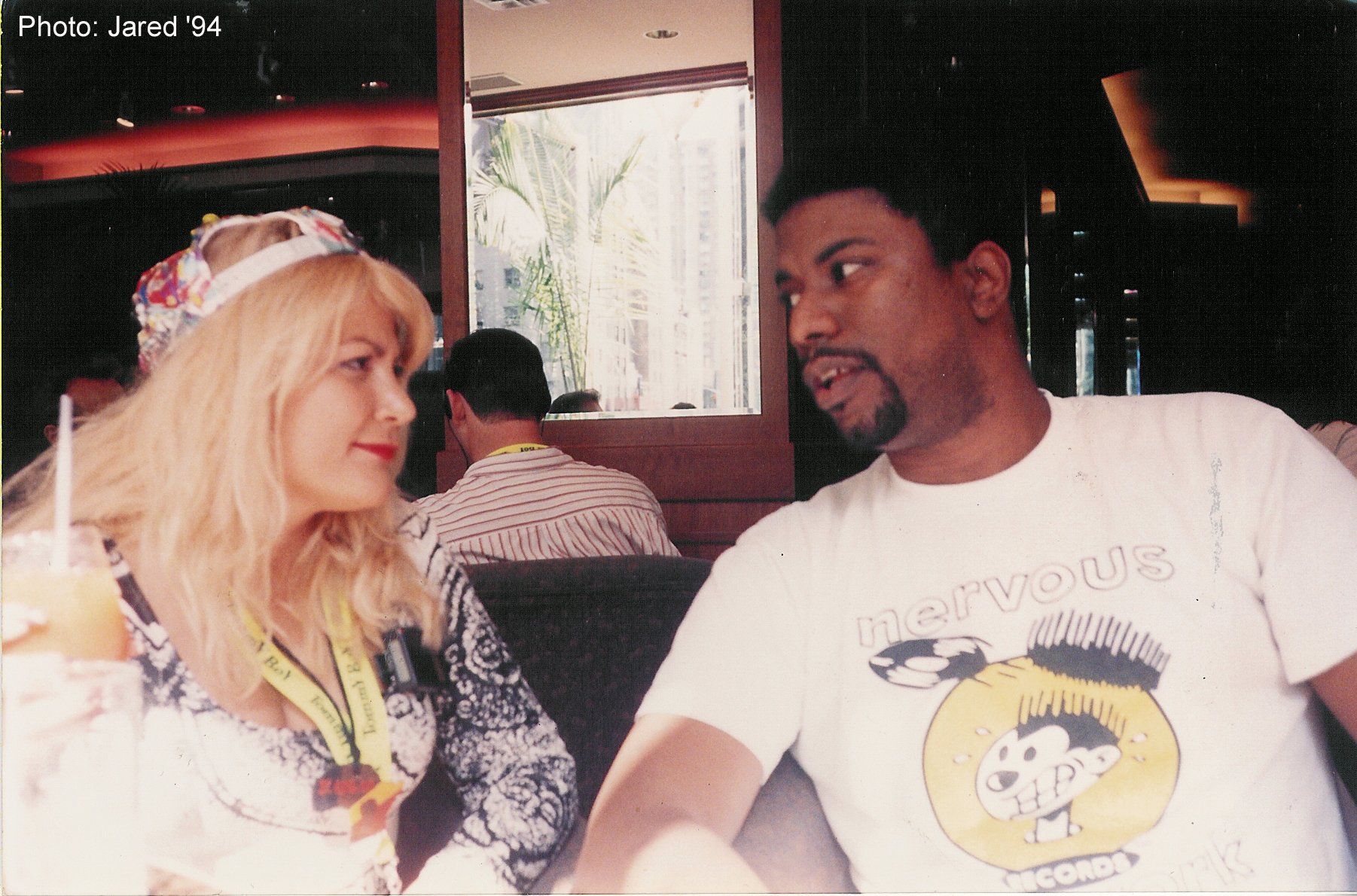 A man and a woman are sitting at a table and the man is wearing a snoopy shirt