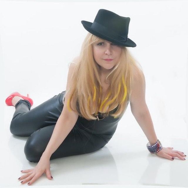 A woman wearing a black hat is kneeling on the floor